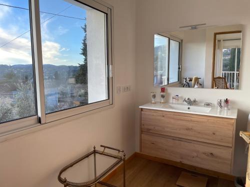 une salle de bain avec un lavabo, un miroir et une fenêtre dans l'établissement VILLA Rayon d'Or, à Peymeinade