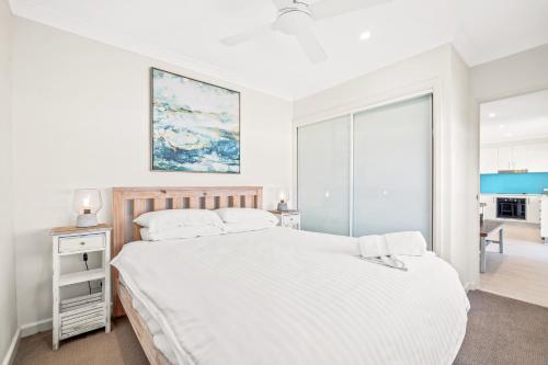 a white bedroom with a large bed and a window at Seaside Symphony, Sleep and Wake to Ocean Waves in Wamberal