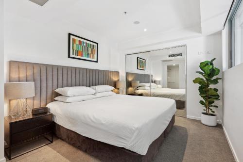 a bedroom with a large white bed and a mirror at Sleek 1-Bed With Rooftop Pool & Amazing City Views in Brisbane