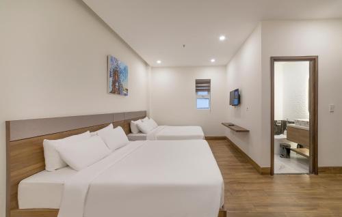 a white bedroom with a large bed and a couch at TALA Dalat Hotel in Da Lat