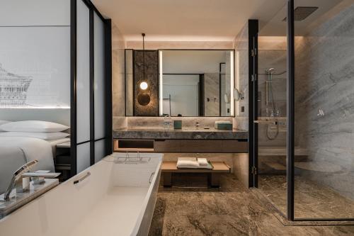 a bathroom with a tub and a sink and a shower at Wuhan Marriott Hotel Wuchang in Wuhan