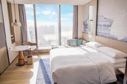 een slaapkamer met een groot bed en een groot raam bij Wuhan Marriott Hotel Wuchang in Wuhan