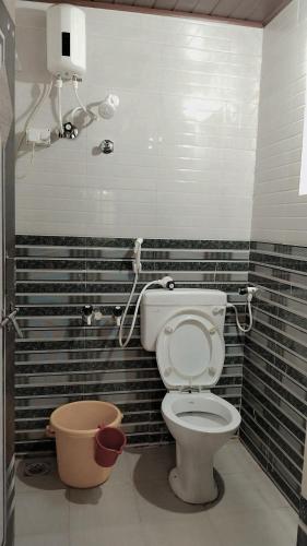 a toilet in a bathroom with black and white tiles at Deepu Guest house in Gokarna