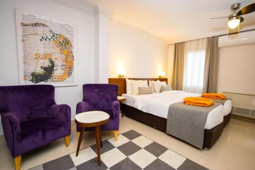 Hotel Pier Bodrum Marina في بودروم: غرفة في الفندق بسرير وكرسيين ارجوانيين