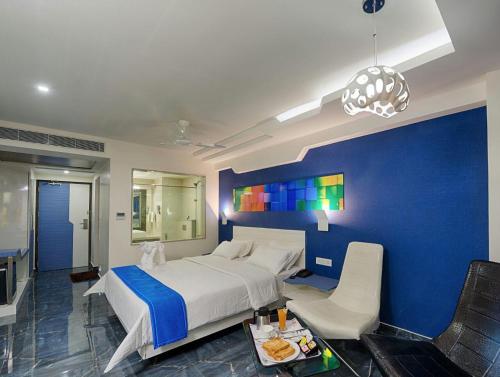 a bedroom with a large bed and a blue wall at Hotel Vijay Elanza in Coimbatore
