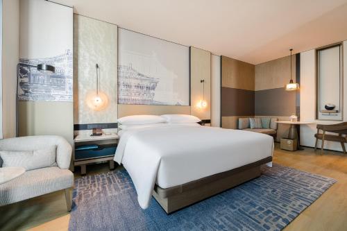 a bedroom with a large white bed and a chair at Wuhan Marriott Hotel Wuchang in Wuhan