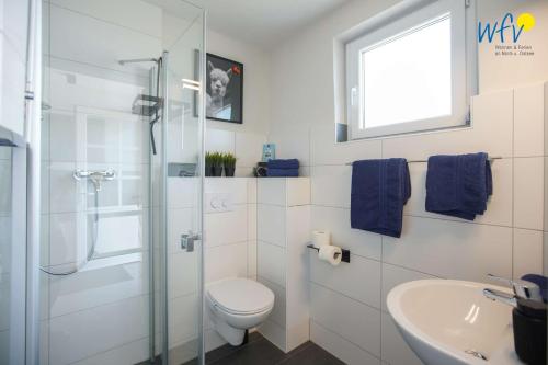 y baño con ducha, aseo y lavamanos. en Ferienhäuser Weerts Gatt Ferienhaus Lüttje Huske en Borkum