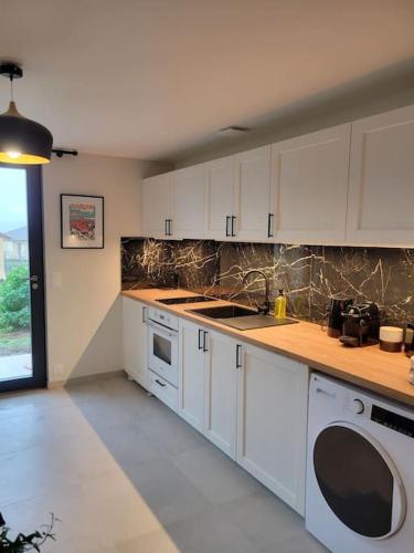 une cuisine avec des armoires blanches et un four à plaques de cuisson dans l'établissement Studio en rez-de-jardin, à Gourdon