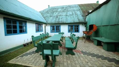 a group of green picnic tables in front of a building at Country cottage in Nuwara Eliya