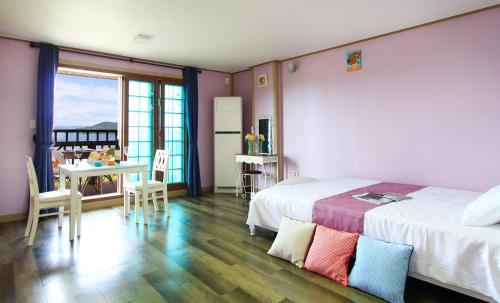 Un dormitorio con 2 camas y una mesa con comedor. en Paper island pension, en Tongyeong