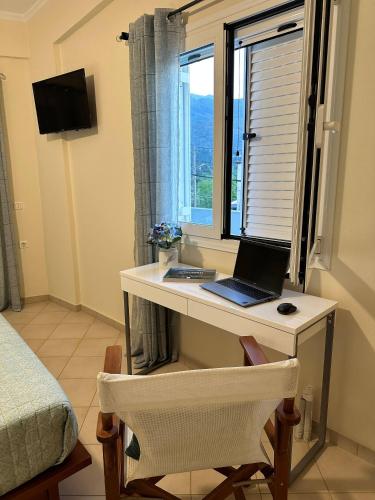a desk with a laptop on it in a room with a window at Glikanisos House Nipos - ideal for hikers and families 2bd, 6pl, 10min to beach in Nípos