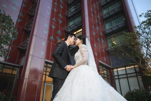 a bride and groom kissing in front of a building at Chatrium Grand Bangkok in Bangkok