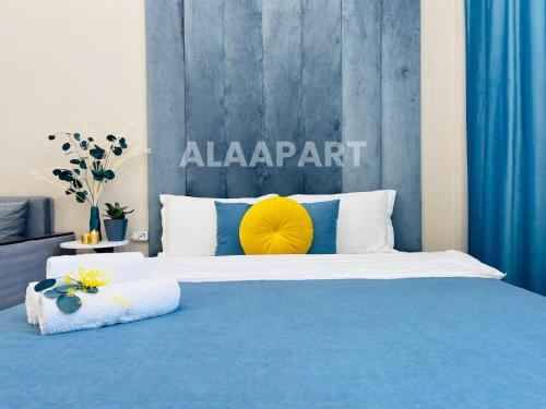 a bedroom with a blue and white bed with a yellow pillow at 396I1 Blue Horizon Apartments Sholpan city in Almaty
