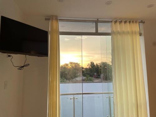 a window with a curtain and a television in a room at Hurin Hotel in Ica
