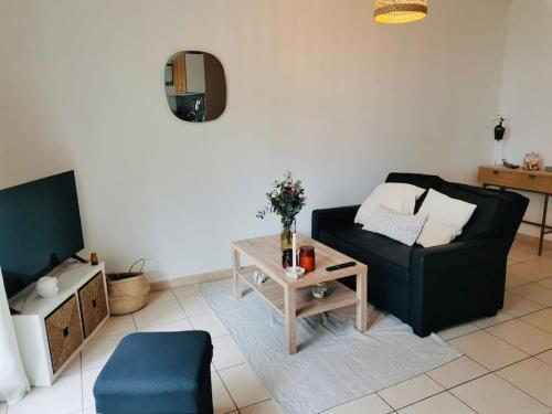un salon avec un canapé noir et une table dans l'établissement Le cosy montpelliérain T3 avec parking, à Montpellier