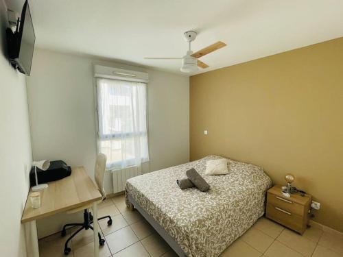 une chambre avec un lit, un bureau et une fenêtre dans l'établissement Le cosy montpelliérain T3 avec parking, à Montpellier