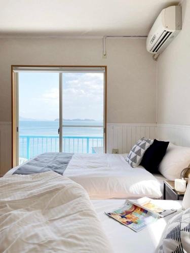 a bedroom with two beds and a view of the ocean at bLOCAL AO house - 1 BR House with Ocean View Few min walk to the beach in Suo Oshima