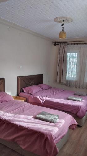 two beds in a bedroom with purple sheets at Emre's Stone House in Göreme