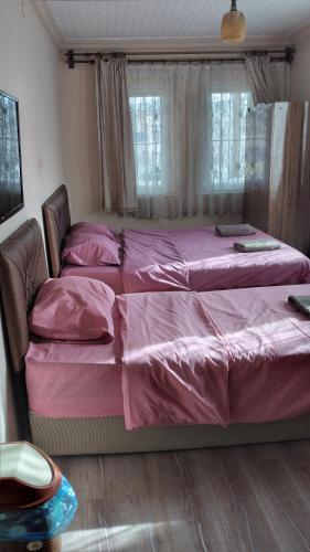 a large bed with pink sheets in a bedroom at Emre's Stone House in Göreme