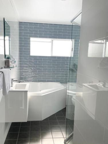 a white bathroom with a tub and a sink at Huskisson Beach Motel in Huskisson