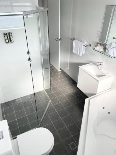 a bathroom with a shower and a toilet and a sink at Huskisson Beach Motel in Huskisson
