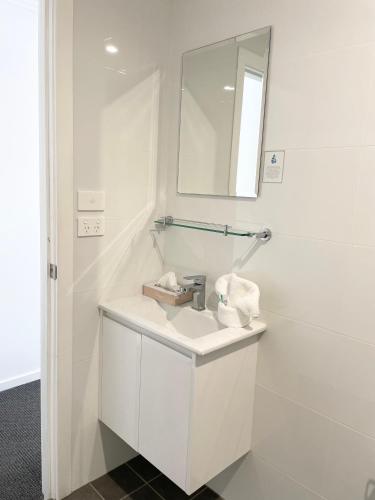 a white bathroom with a sink and a mirror at Huskisson Beach Motel in Huskisson