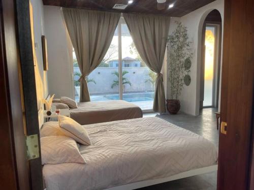 two beds in a bedroom with a view of a pool at CASA LUNA ¡Piscina y Playa! in La Ceiba