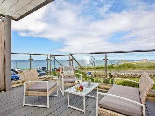 a deck with chairs and a table and a view of the ocean at 15 Ocean Gate Newquay in Crantock