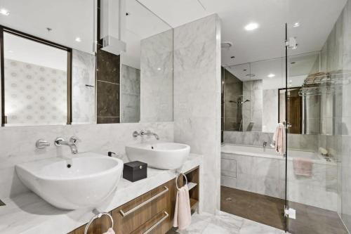Grand St Kilda 2-story Sub-Penthouse في ملبورن: حمام مع مغسلتين ودش وحوض استحمام