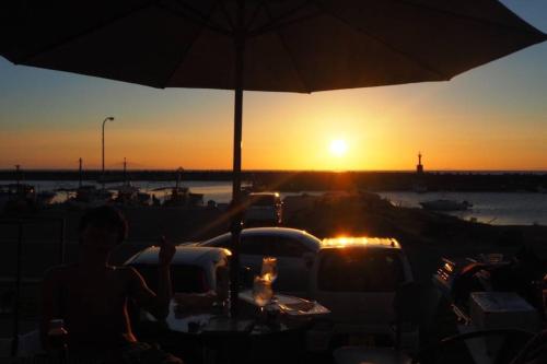 a person sitting at a table with the sunset in the background at Yiyi Villa Awaji 淡路島西海岸夕日百選のvilla BBQ釣りゴルフ in Awaji