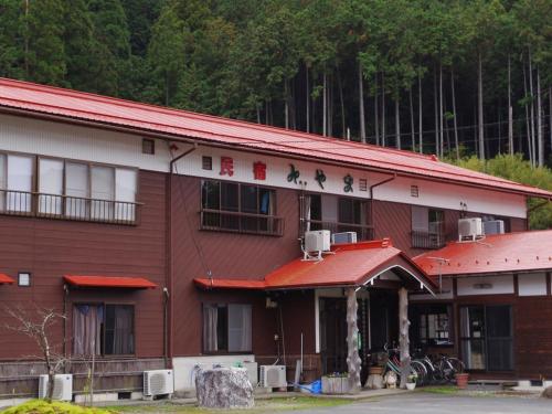 a red and white building with a red roof at 民宿みやま in Ōno