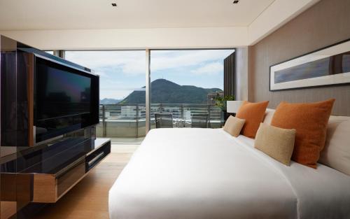 a bedroom with a large white bed and a flat screen tv at Nina Hotel Island South in Hong Kong