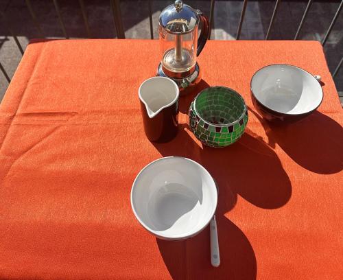 un tavolo arancione con due tazze e ciotole sopra di Varigotti for lovers a Varigotti