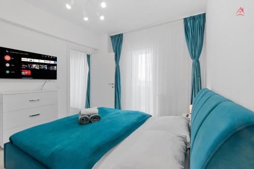 Schlafzimmer mit einem Bett mit blauer Bettwäsche und einem TV in der Unterkunft New World Militari Grand Studio 2 in Bukarest