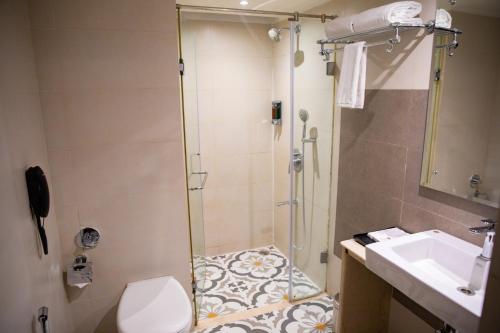 a bathroom with a shower and a toilet and a sink at Grand Continent Secunderabad A Sarovar Portico Affiliate Hotel in Secunderabad