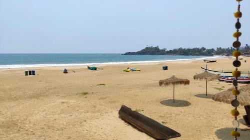 a beach with some straw umbrellas and the ocean at Royal cottage in Palolem