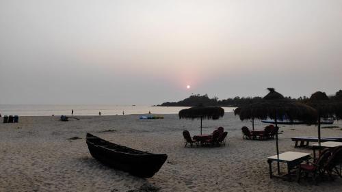 a beach with chairs and tables and umbrellas at Royal cottage in Palolem