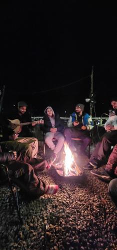 a group of people sitting around a fire at night at Safar Hostel Manali in Manāli