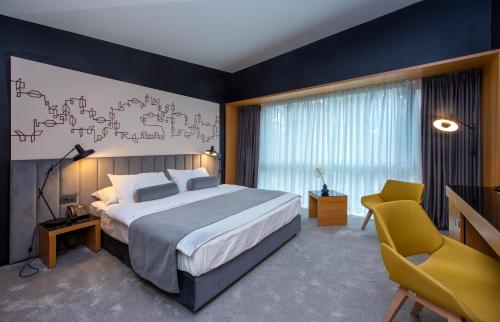 a bedroom with a large bed and a yellow chair at Park Boutique Hotel in Varaždin