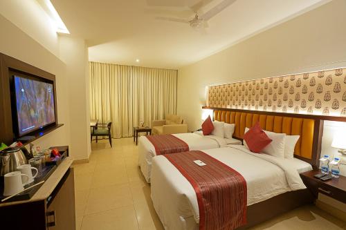 Cette chambre comprend deux lits et une télévision. dans l'établissement Grand Continent Secunderabad A Sarovar Portico Affiliate Hotel, à Secunderābād