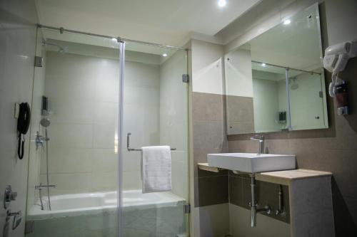 La salle de bains est pourvue d'une douche, d'un lavabo et d'une baignoire. dans l'établissement Grand Continent Secunderabad A Sarovar Portico Affiliate Hotel, à Secunderābād
