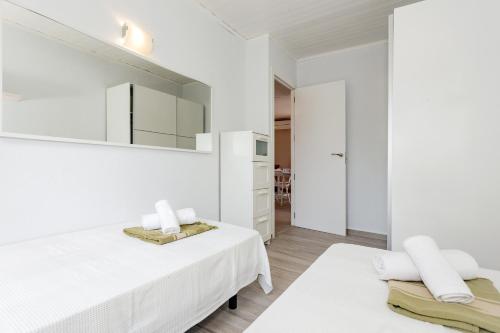 um quarto branco com 2 camas e um espelho em Cova des moro 8 em Cala'n Bosch