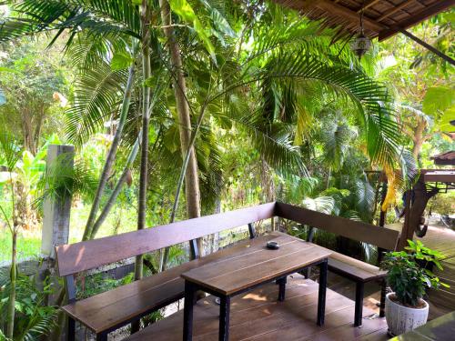 un banc en bois installé au-dessus d'une terrasse en bois dans l'établissement Jungle Vibes, à Thongsala