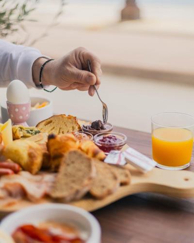 a person eating a plate of food with toast and orange juice at Hotel Kyani Akti in Xylokastron