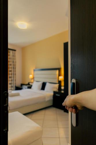 a person opening a door to a bedroom with two beds at Hotel Kyani Akti in Xylokastron