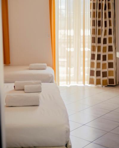 two beds in a room with white towels on them at Hotel Kyani Akti in Xylokastron