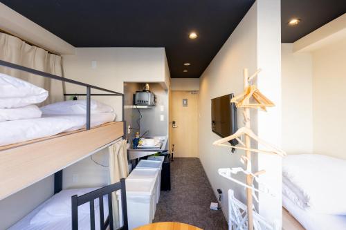 a dorm room with two bunk beds and a table at HOTEL HARE BARE 3min walk from Kiba Station in Tokyo