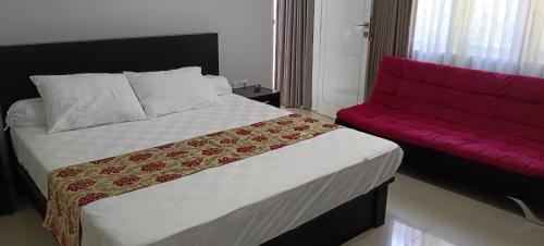 a bedroom with a bed and a red couch at Casa Raya in Kuta