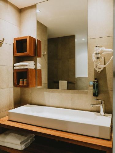 a bathroom with a large white sink and a mirror at Hotel Le Saint Pierre ÎLe De La Reunion. in Saint-Pierre