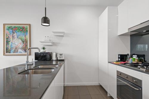 a white kitchen with a sink and a counter at A taste of paradise in inner city suburbia in Melbourne
